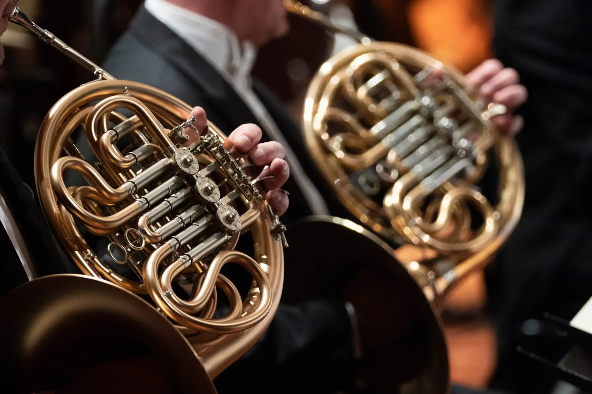 Close-up of French horn players performing in a symphony orchestra