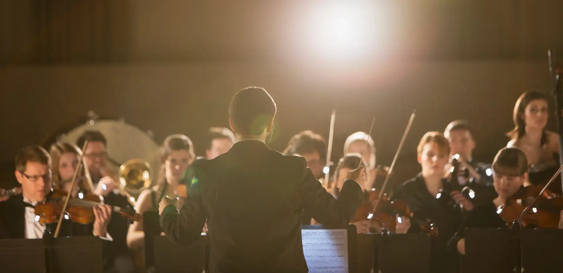 Conductor leading a symphony orchestra on stage